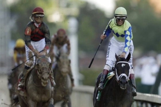 Web photo of a horse race: the leading jockey in lime green and blue silks rides a dark horse, with more jockeys and horses behind. Boxes 1 and 2 mark the jockey and horse described in the record.